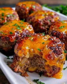 meatballs covered in cheese and sauce on a white plate with green garnish