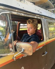 a woman sitting in the driver's seat of an old van looking out the window