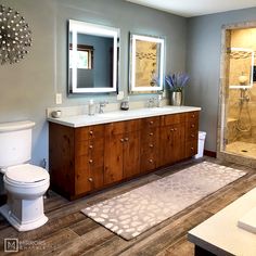 a bathroom with two sinks, a toilet and a large mirror in it's center