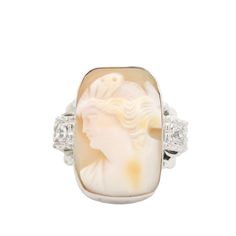 Celebrate the artistry of a bygone era with this exquisite 10K yellow gold vintage cameo ring. Featuring an intricately carved cameo of a woman, this ring is more than just a piece of jewelry—it's a timeless work of art. The delicate portrait is beautifully framed by a halo of sparkling diamonds, totaling 0.25 carats, adding a touch of luxury to this classic piece. Material: 10 Karat Yellow Gold Design: Cameo of a Woman Gemstones: 0.25 Carats of Diamonds Total Weight: 8.8 grams A Journey Through Luxury Elegant Cameo Ring, Art Deco Cameo Collectible Rings, Luxury Yellow Gold Cameo Rings, Collectible White Cameo Rings, Antique Cameo Ring Collectible, Grace Symbol, Vintage Cameo, Cameo Ring, Cameo Jewelry