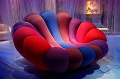 a colorful chair sitting on top of a blue floor next to a curtained wall