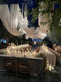 a table with candles and chandeliers is set up for a formal function at night