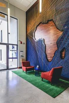 an office lobby with chairs and artwork on the wall