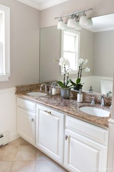 a bathroom with double sinks and white cabinets