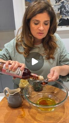 a woman pouring olive oil into a glass bowl