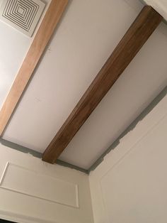 an unfinished wooden beam hangs from the ceiling in a room with white walls and wood trim