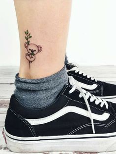 a small tattoo on the ankle of a woman with a koala bear and leaves