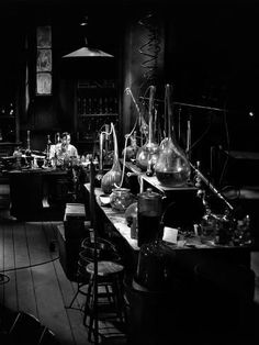 black and white photograph of lab equipment in an old fashioned laboratory room with stools