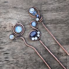 three metal flowers with blue and white stones on them sitting on a wooden table next to some wire