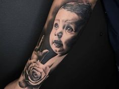 a man's arm with a black and white tattoo on it, depicting a child holding