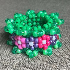 there are many beads that are on the table together and one is pink, green, and purple