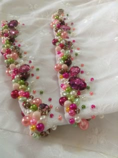 two necklaces made out of beads on a white cloth with lace around the edges