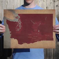 a man holding up a map of the united states in front of a wooden fence