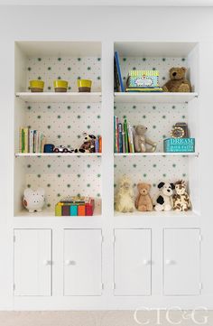 two white bookcases with green stars on them and stuffed animals in the middle