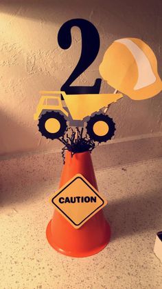 a traffic cone with two construction vehicles on it and a sign that says 2 in the middle