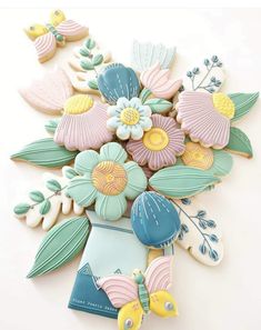 cookies decorated with flowers and seashells are arranged on a white surface, including one cookie