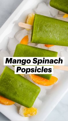 three popsicles with green and orange toppings sitting on ice cubes in a white tray