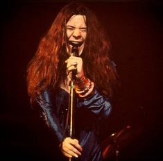 a woman with long hair holding a microphone in her hand and singing into the microphone