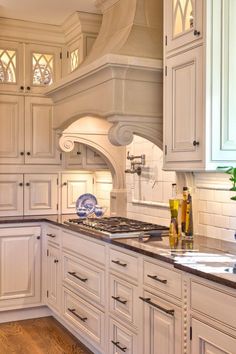 a large kitchen with white cabinets and wood flooring on the counter tops, along with an oven