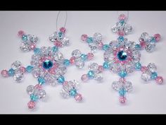 two snowflakes made out of glass beads on a white surface with blue and pink accents