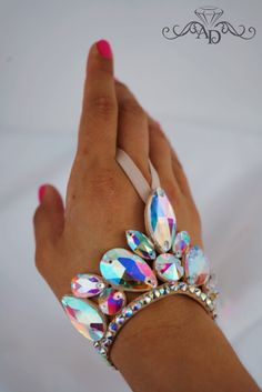 a woman's hand holding onto a bracelet with lots of jewels on top of it