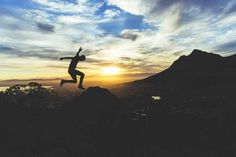 a person jumping up into the air on top of a mountain