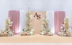 an arrangement of flowers on the side of a stage with drapes and monograms