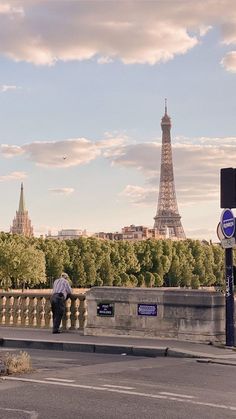 a man is sitting on a bridge looking at the eiffel tower in paris