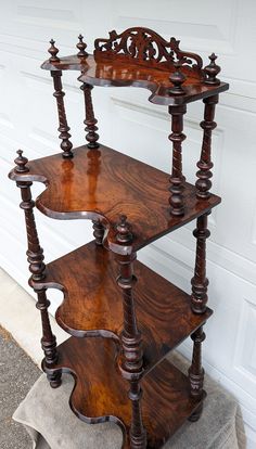 a three tiered wooden shelf sitting in front of a garage door