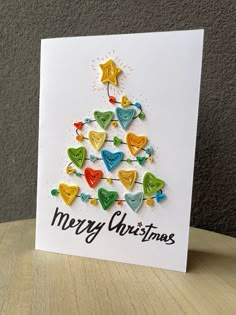 a merry christmas card on a table with a tree made out of hearts and stars