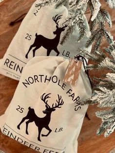 two bags with deer on them sitting next to a christmas tree