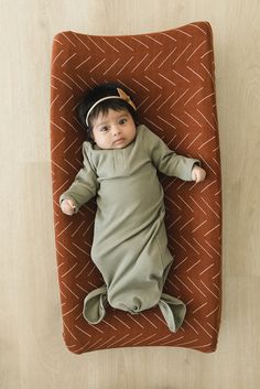 a baby laying on top of a brown blanket