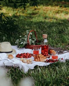 a picnic with strawberries, croissants and bread on a blanket in the grass