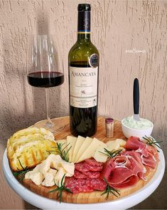 a bottle of wine and some food on a table next to a glass of wine