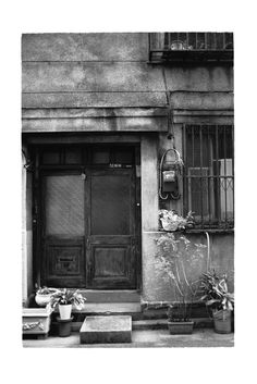 black and white photograph of an old building with potted plants