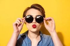 a woman wearing sunglasses making a funny face with her tongue sticking out from under the glasses