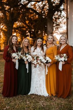 a group of women standing next to each other holding bouquets in front of trees