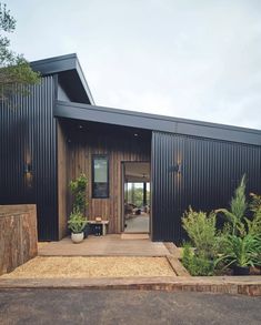 the entrance to a black house with wooden steps leading up to it and potted plants on either side