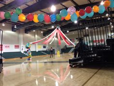 some people are standing in the middle of a gym with many balloons hanging from the ceiling