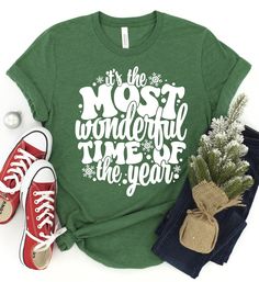 ~~It's The Most Wonderful Time Of The Year~~ Screen printed design on a soft style unisex fit tee.  Choose your shirt color and style from the menu. The design is white as shown. *2nd size chart is for a sweatshirt option. **Example shirt color is heather grass green** SHIRT DETAILS: -Heather Colors : 52% combed ringspun cotton & 48% polyester  -Solid Colors - 4.3 oz 100% preshrunk cotton  -Shoulder-to-shoulder taping -Double-needle stitched sleeves and bottom hem -Unisex sizes are similar to a Winter Short Sleeve Tops With Letter Print, Short Sleeve Tops With Letter Print For Winter, Christmas Short Sleeve Top With Funny Text, Holiday Green Tops With Letter Print, Green Holiday Tops With Letter Print, Christmas Cotton T-shirt With Text Print, Christmas Gift Tops With Funny Text, Green Christmas Letter Print Top, Christmas Funny Text Top As Gift