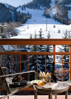 two chairs and a table with food on it in front of a snowy mountain view