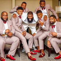 a group of men in suits and red shoes posing for a photo with their arms around each other