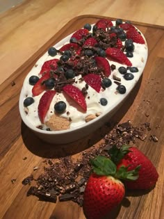 a dessert with strawberries and chocolate shavings on a cutting board next to it