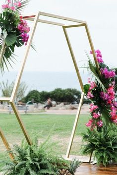 some pink flowers and greenery are on display in front of an open hexagonal structure