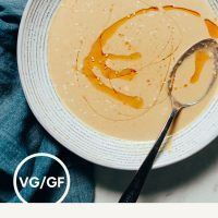 a white bowl filled with soup next to a spoon