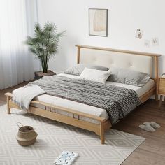 a bed sitting on top of a wooden floor next to a potted palm tree