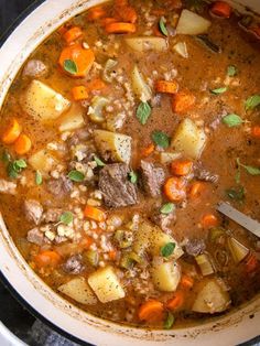 a pot filled with stew and carrots on top of a stove