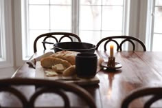 a wooden table topped with lots of food next to a candle and some glasses on top of it