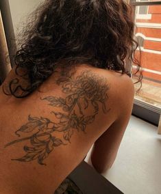 a woman with a tattoo on her back looking out the window