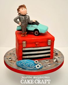 a cake with a man sitting on top of a red suitcase and blue glass object